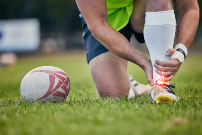 Rugby player receiving first aid for an ankle injury on the pitch
